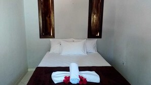 A hotel room with a bed, white linens, a dark brown bedspread, and a rolled towel with red flowers. - Pousada Pôr do Sol (Maraú)