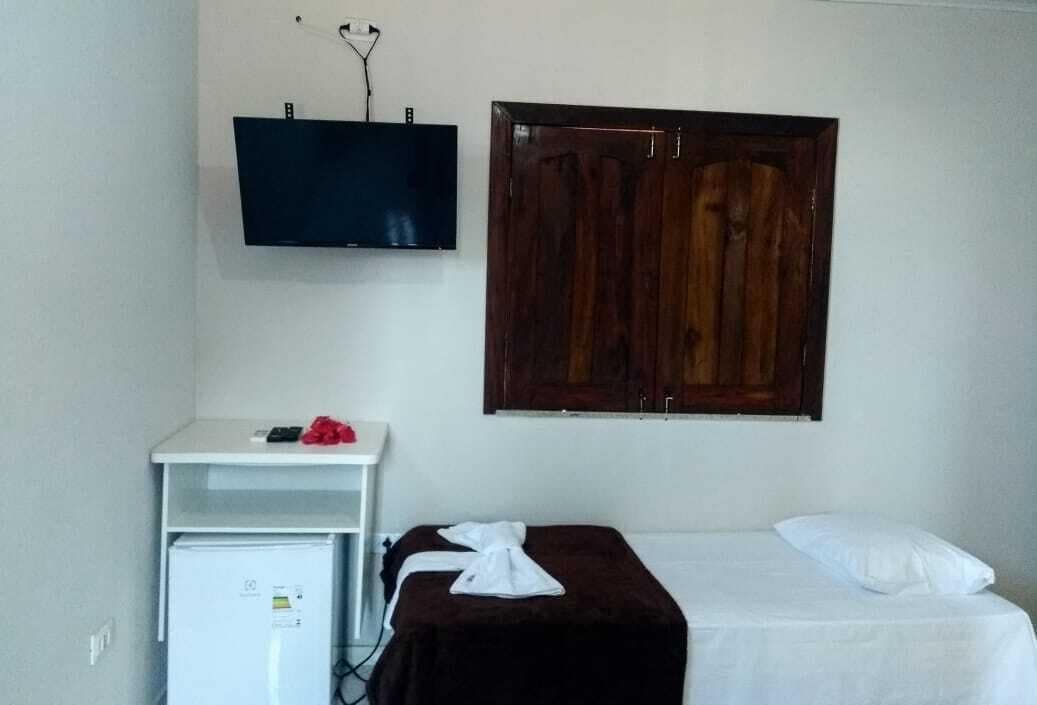 Una habitación con una cama, un escritorio pequeño con televisión y un armario.