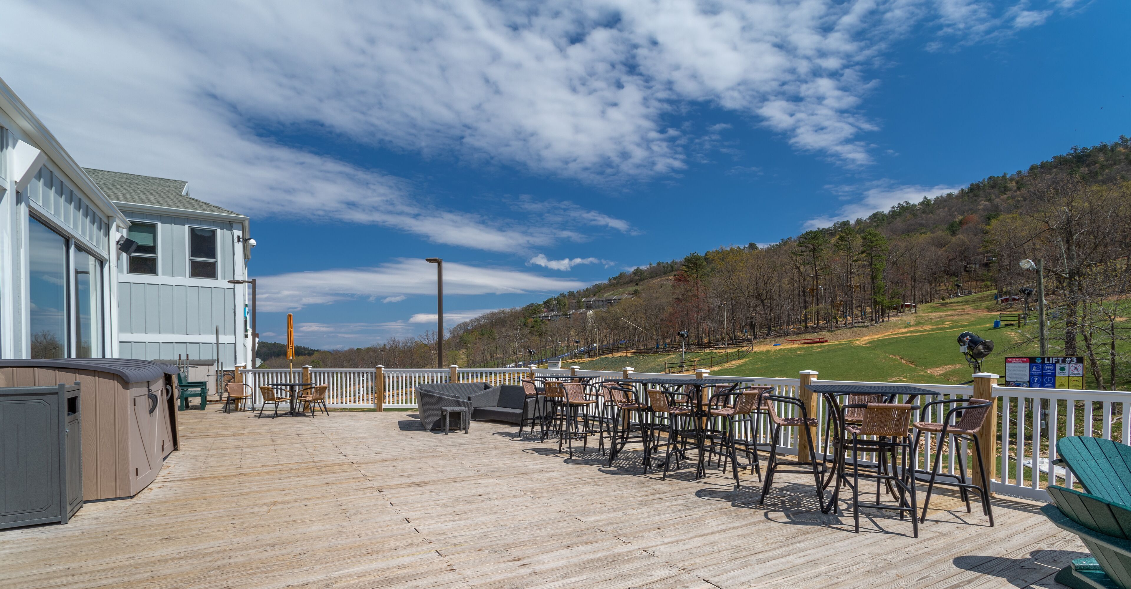Una terraza de madera con mobiliario exterior, un jacuzzi y vistas a un campo de golf.