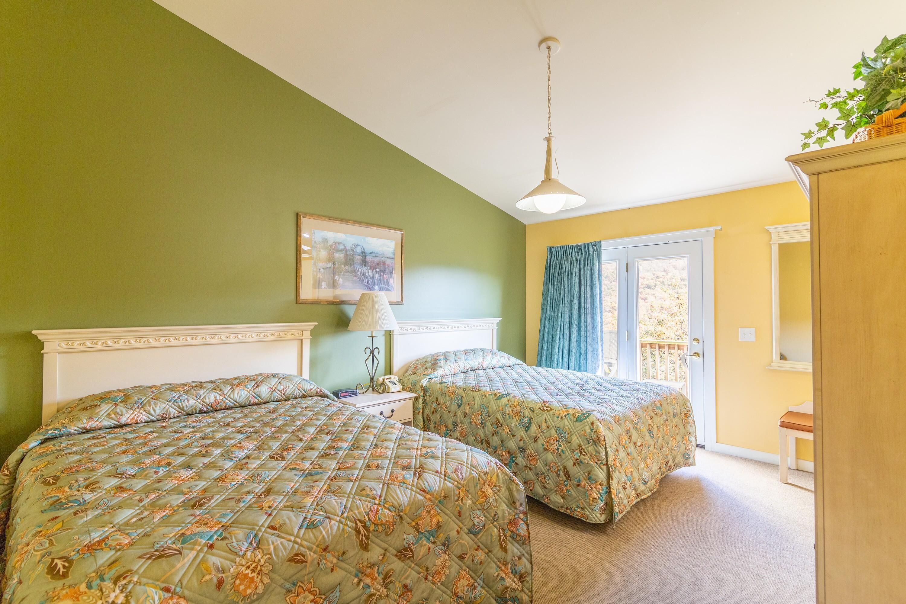 A bedroom with two beds, a nightstand, a lamp, and a painting on the wall.