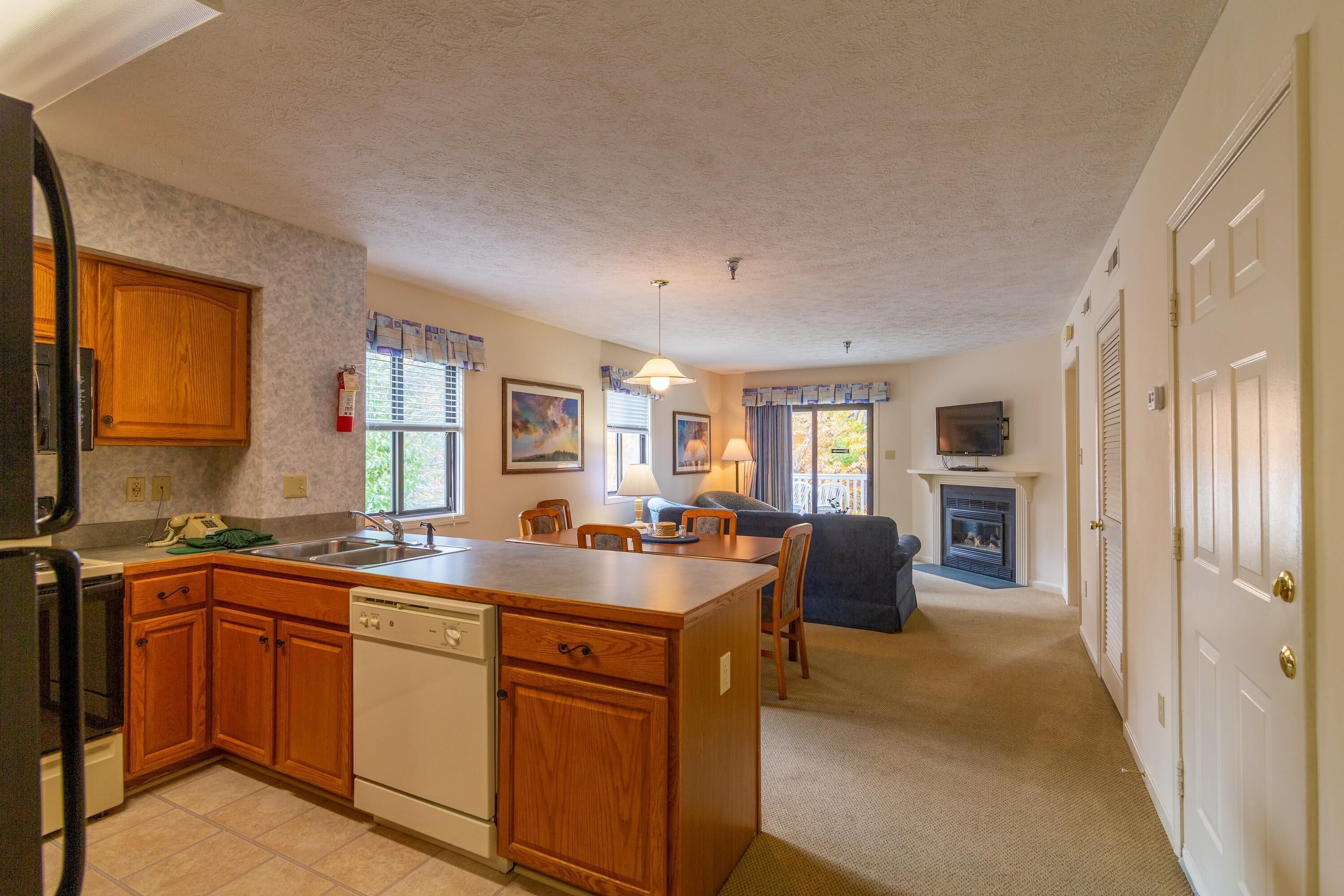 A kitchen with wooden cabinets, a dishwasher, and a dining area with a table and chairs.