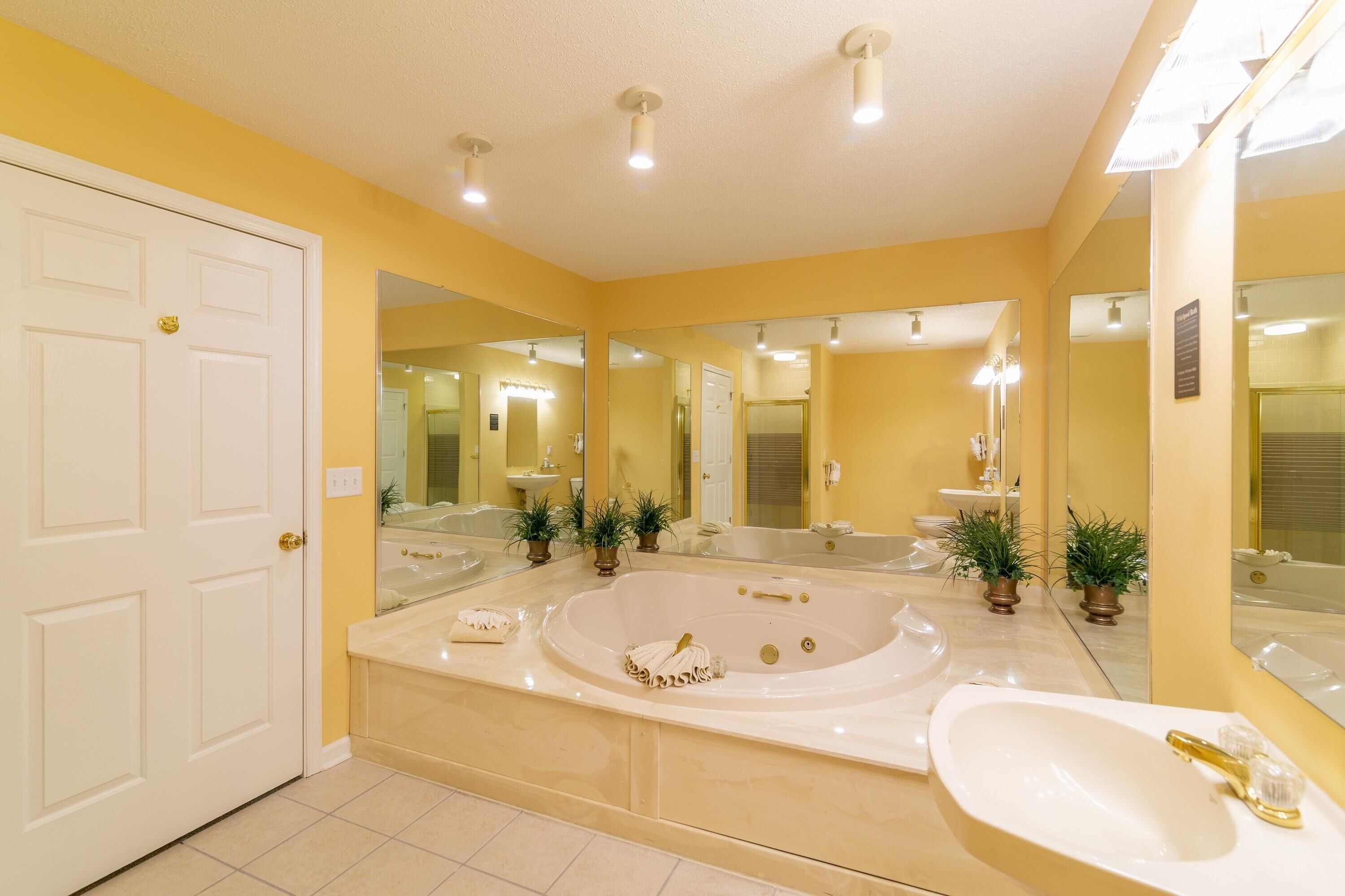 Une salle de bain moderne dotée d’une grande baignoire, d’un lavabo séparé et de plusieurs miroirs.