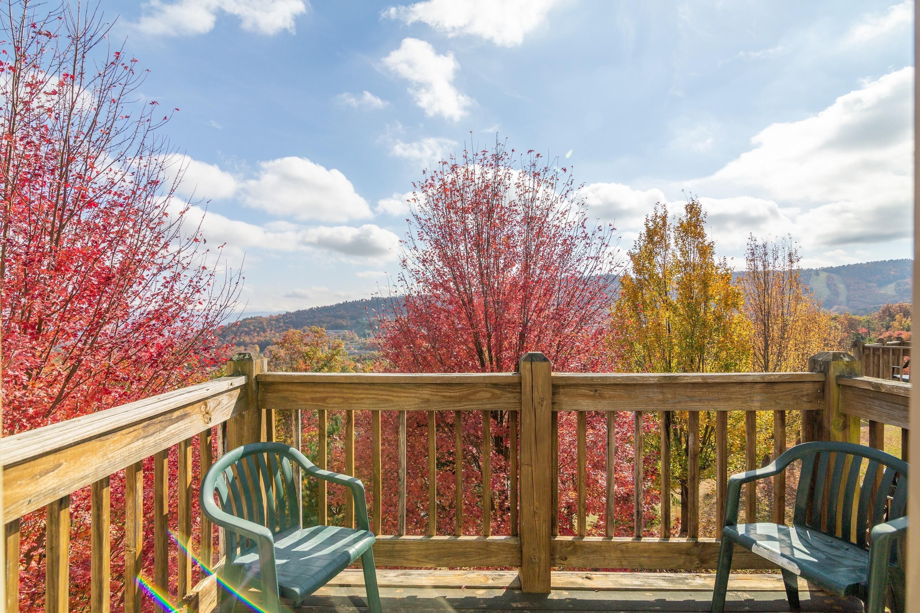 A wooden deck with two green chairs and a wooden railing.