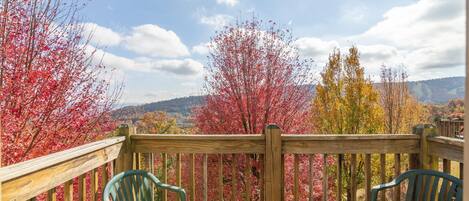 A wooden deck with two green chairs and a wooden railing.