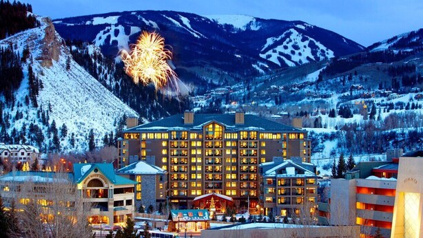 A large hotel with multiple floors and a central courtyard, surrounded by snow-covered mountains and a ski resort. - Riverfront Resort and Spa - Luxury Studio Suite: SKI IN / SKI OUT (Avon)