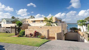 A beachfront property with a large house featuring a brick wall, a balcony, and a view of the sea. - Pelican Sands, 3/83 Soldiers Point Rd - stunning waterfront unit, magical views & air conditioning (Soldiers Point)
