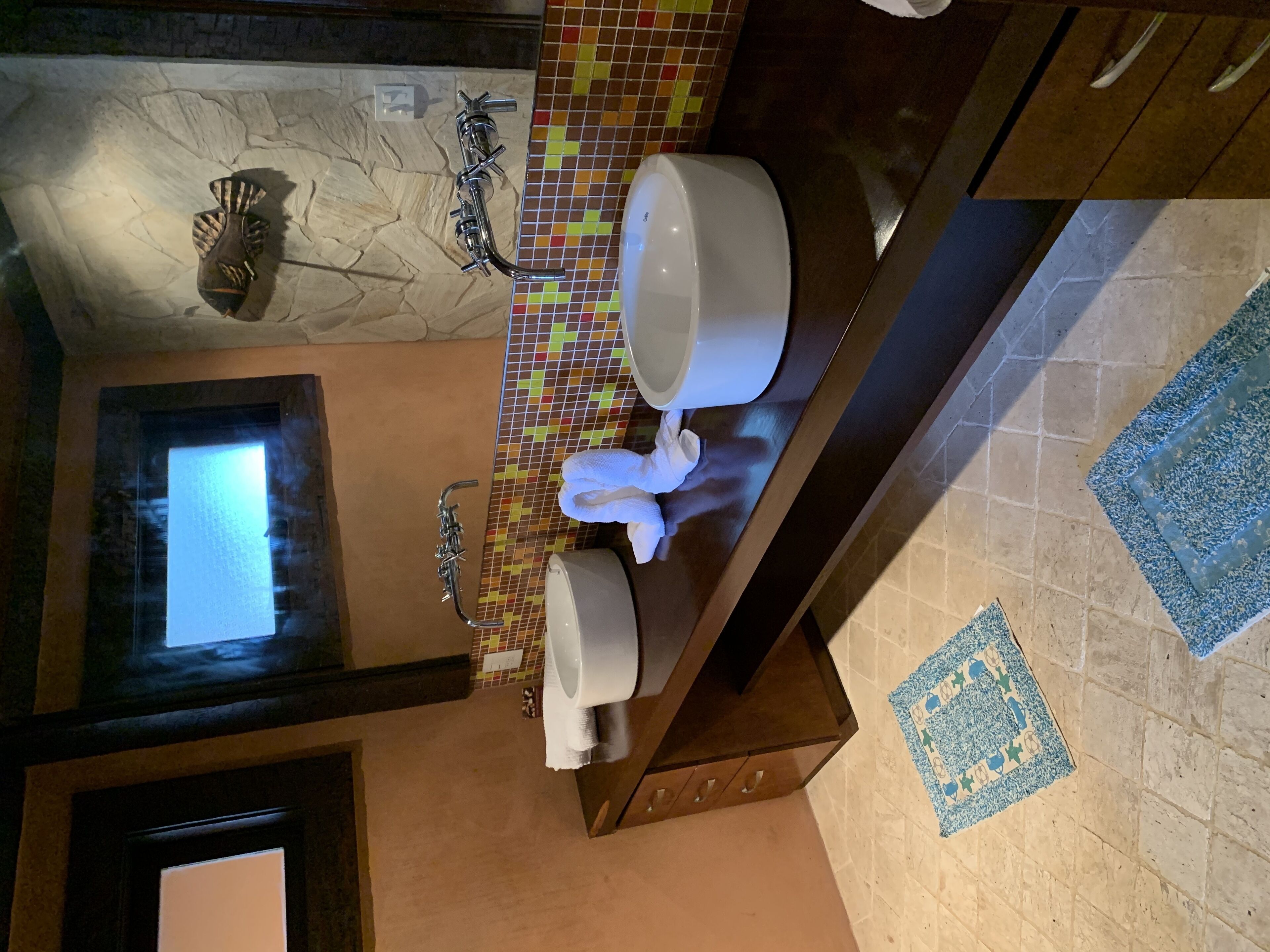 Une salle de bain avec un mur en pierre, un pare-chocs carrelé, des toilettes blanches et un porte-serviettes.