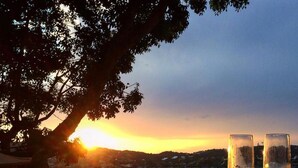 Una vista al atardecer con dos copas de vino en un patio de piedra.