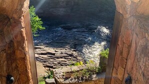 Un arco de piedra que da a una costa rocosa con aguas cristalinas y un arcoíris.