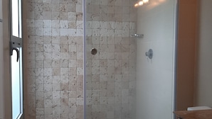 En bruseniche med glasdør, flisebeklædt væg og toilet.