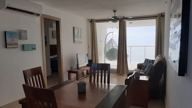 En moderne stue med spiseområde, TV og en balkon med hængestol.