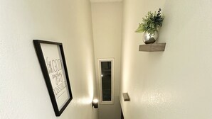 A carpeted staircase with a handrail, a framed inspirational quote, a small potted plant, and a window at the top. - *The Lovely Place* Stunning 3BR 1.5 BA Sleeps 7. Private driveway RV parking.  (Anchorage)