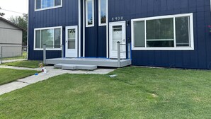 A two-story house with a dark blue exterior, white trim, and a front porch. - *The Lovely Place* Stunning 3BR 1.5 BA Sleeps 7. Private driveway RV parking.  (Anchorage)