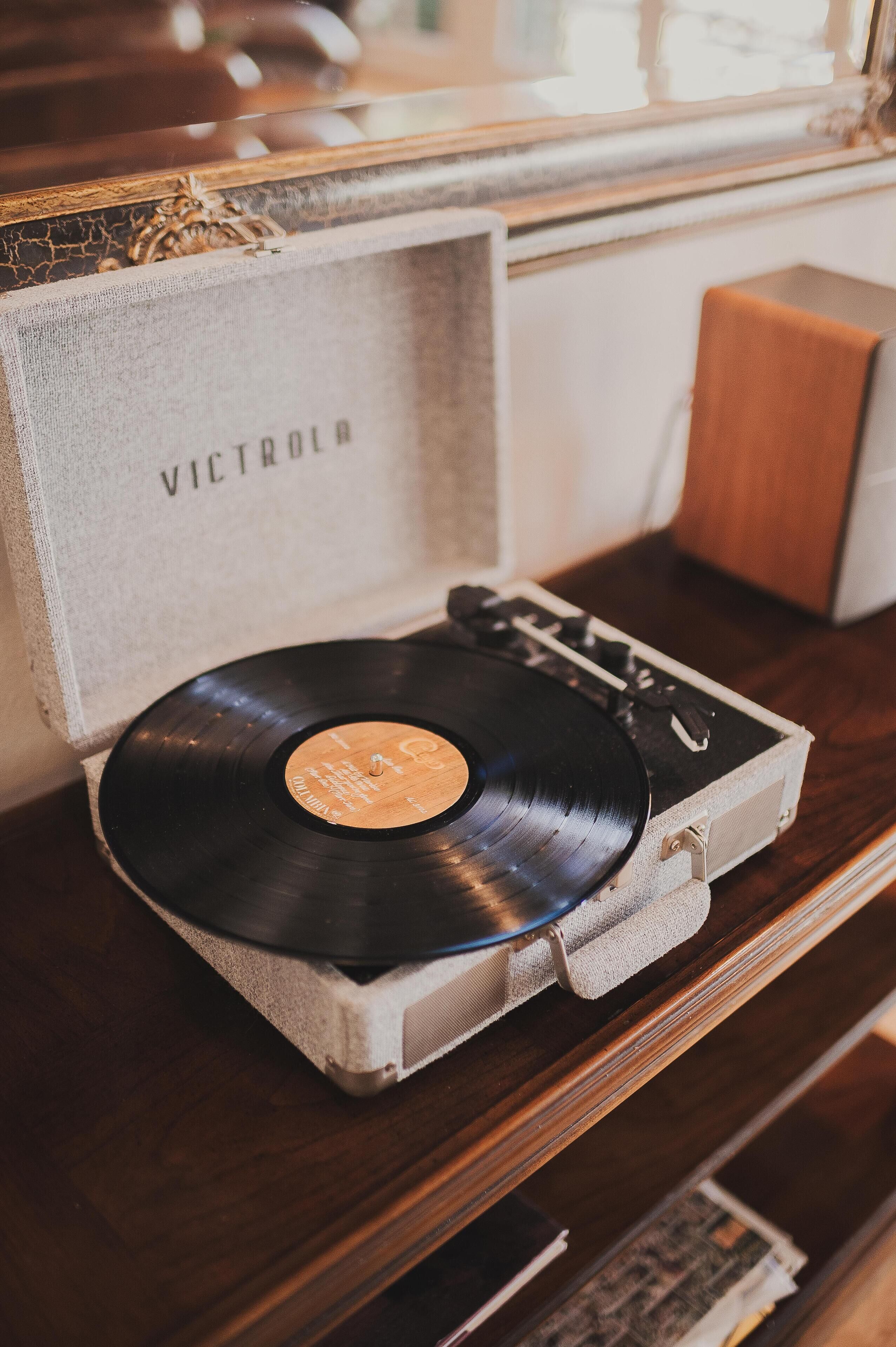 A vinyl record in a wooden crate with the word "VICTROLA" on it, placed on a wooden surface.