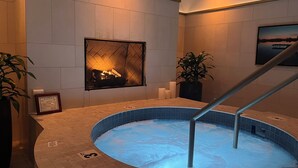 Un jacuzzi con interior de azulejos, un cuadro en la pared y una planta.