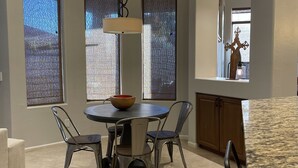 Un comedor moderno con una mesa redonda, cuatro sillas y un colgador de luz.