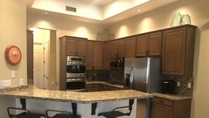 Una cocina moderna con encimeras de granito, electrodomésticos de acero inoxidable y armarios de madera.