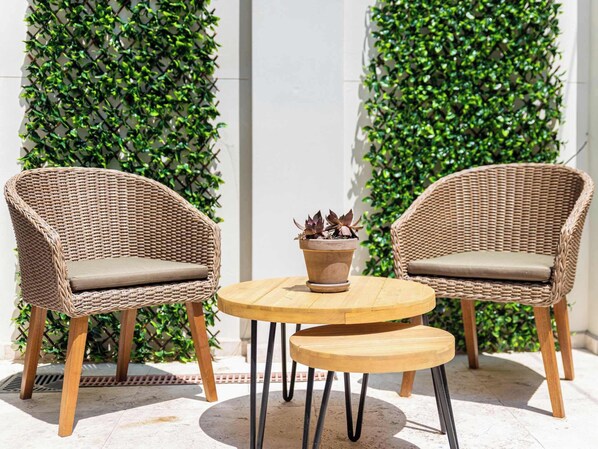 Two wicker chairs with cushions, a small round table, and a potted plant.