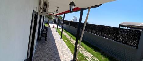 A covered outdoor area with stone flooring, black chairs, and a red awning.