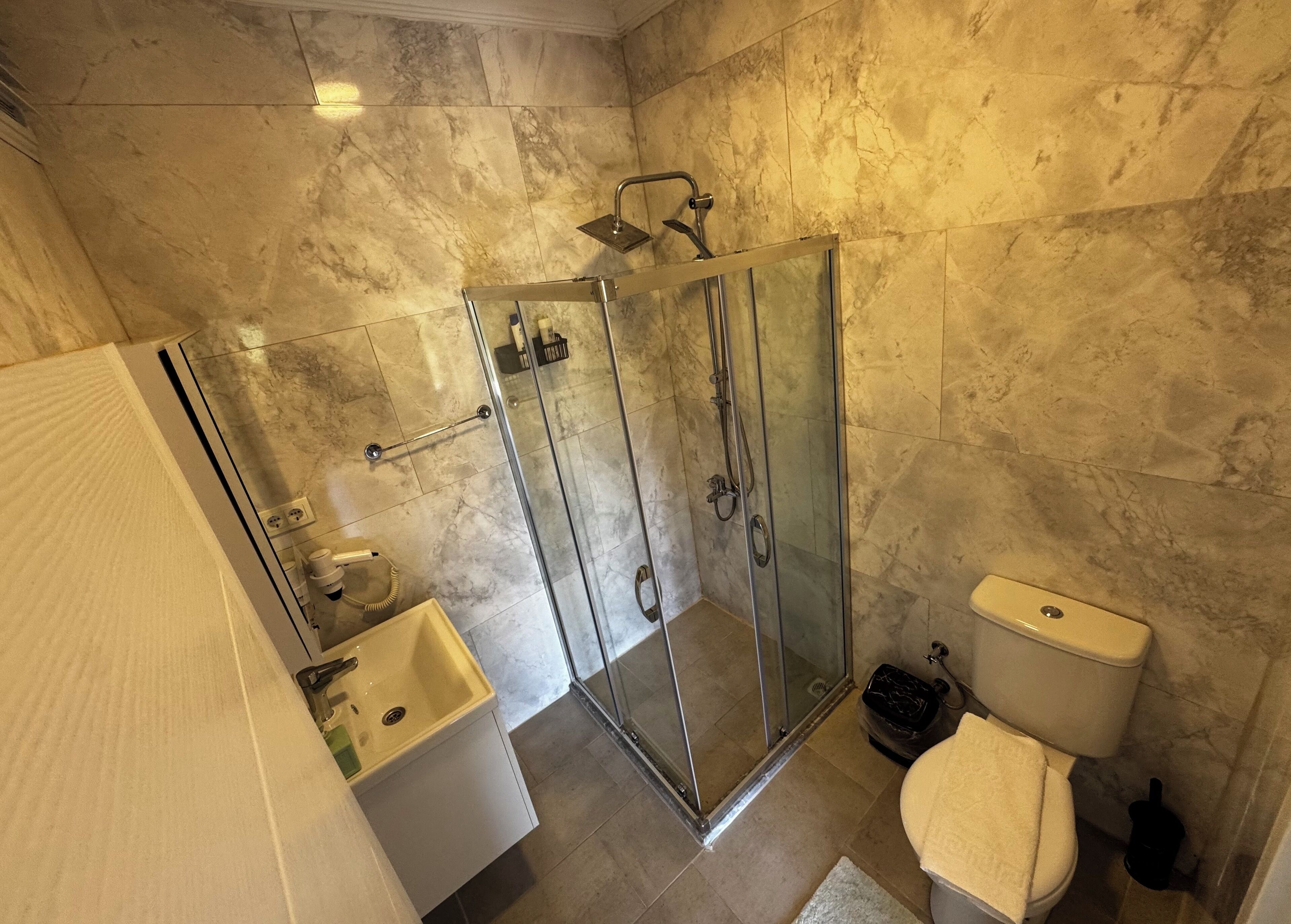 A bathroom with a glass-enclosed shower, a sink, and a toilet.