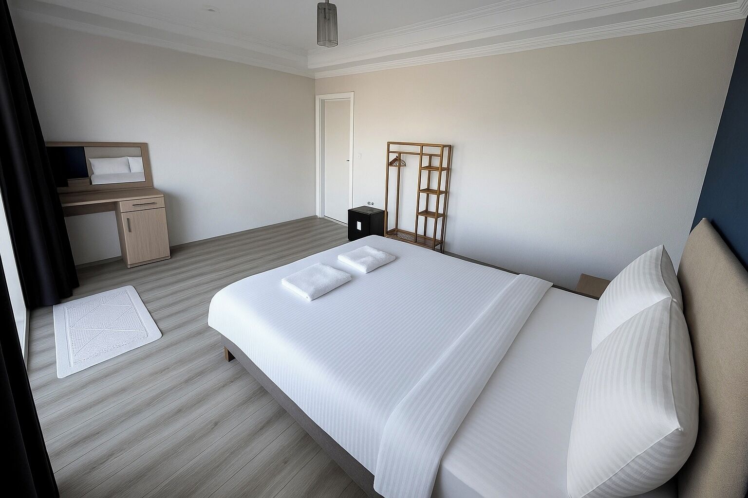 A modern hotel room with a large bed, a desk, and a wardrobe.