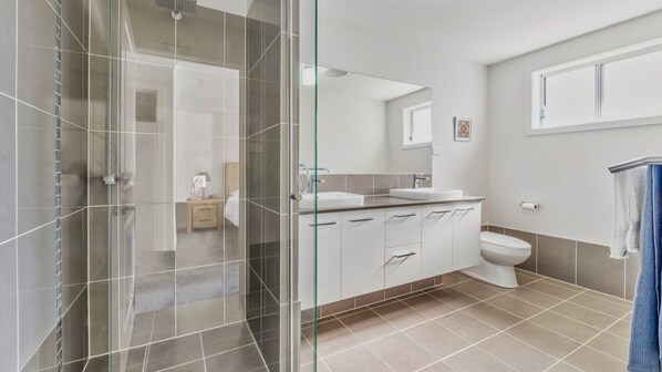 A modern bathroom with a glass shower enclosure, a white sink, and a toilet.