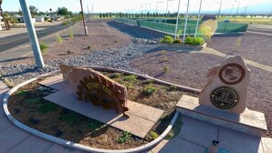 Un parque con un sendero circular, una escultura y una placa.