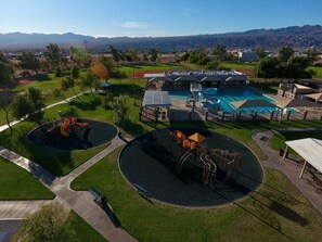 A playground with two circular play areas, a swimming pool, and a building with a covered patio.