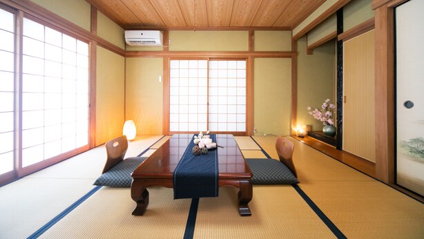 Una habitación japonesa tradicional con suelo de tatami, una mesa de madera baja y paneles de shoji.
