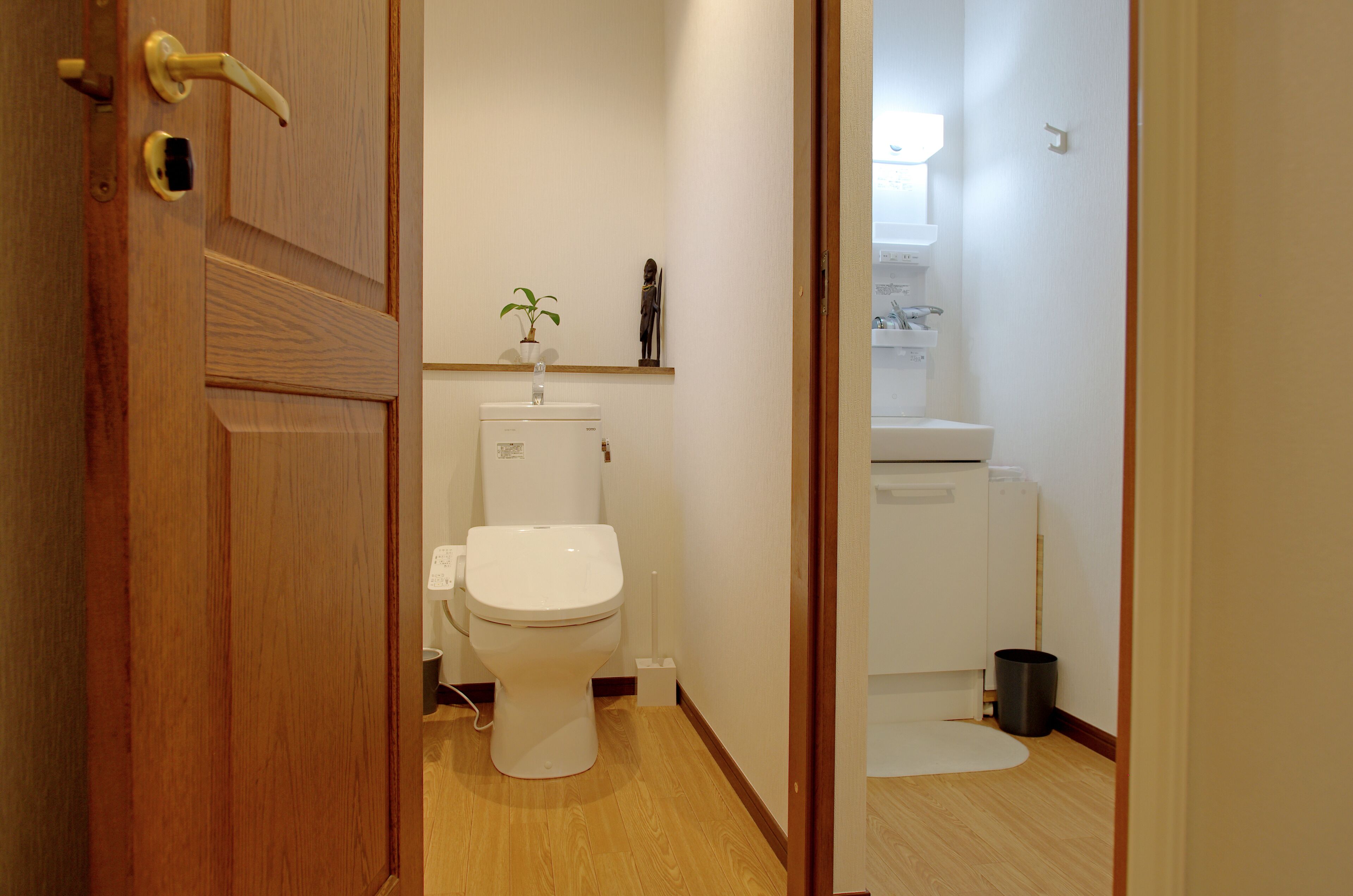 Un baño con inodoro, lavamanos y una planta pequeña en la encimera.