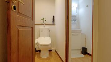 Un baño con inodoro, lavamanos y una planta pequeña en la encimera.