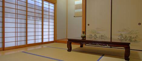 A traditional Japanese room with tatami flooring, sliding doors, and a wooden table.
