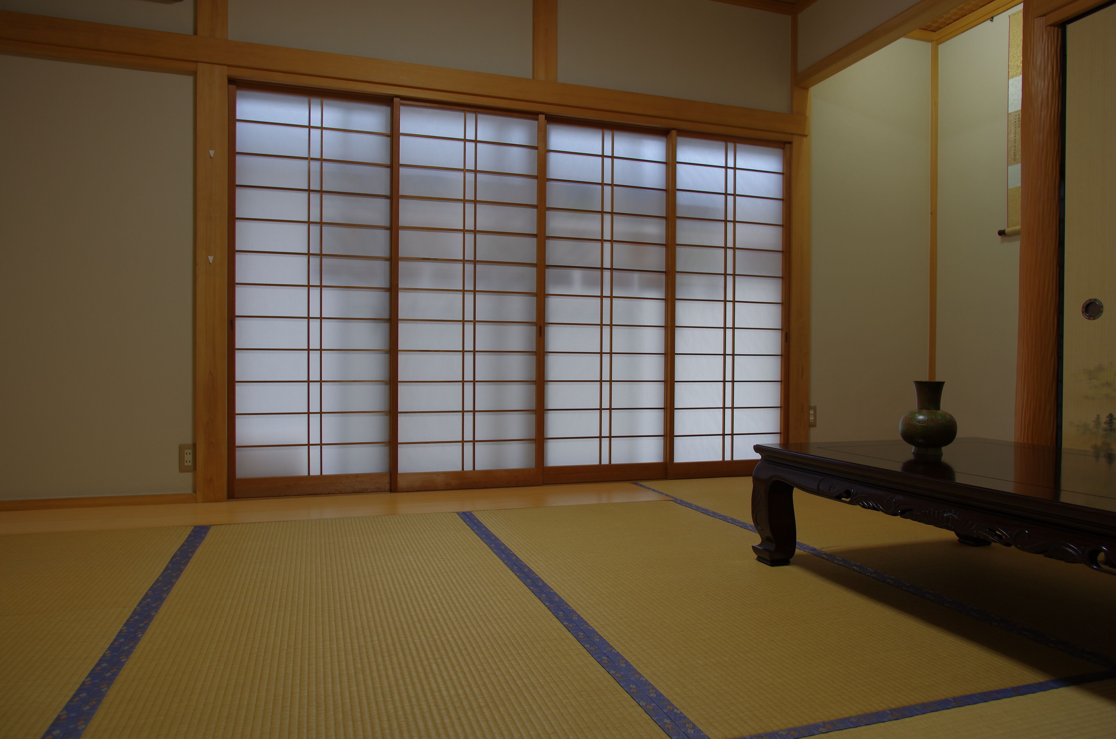 A traditional Japanese room with tatami flooring, a sliding shoji screen, and a dark wooden bench.