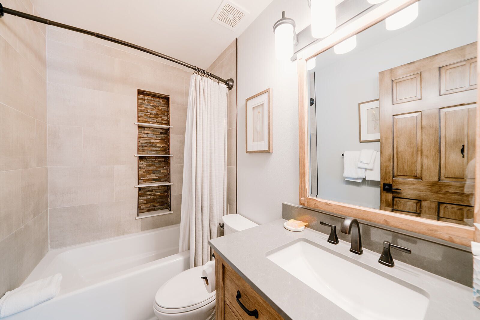 Une salle de bain moderne avec une baignoire, des toilettes, un meuble-lavabo et un grand miroir.