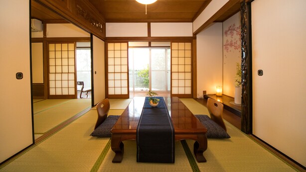 Um quarto japonês tradicional com tatames, uma mesa de madeira baixa e portas deslizantes.