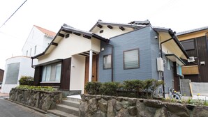Uma casa com parede de pedra, um pequeno alpendre e uma garagem.
