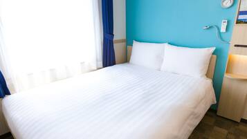 A hotel room with a bed, a nightstand, a clock, and a thermostat.