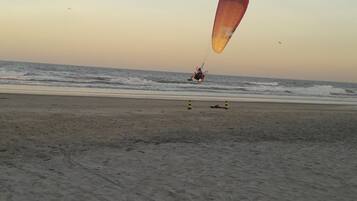 Na praia, areia branca, guarda-sóis
