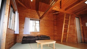 L’intérieur d’une cabane en bois, avec un canapé, une petite table et une échelle.