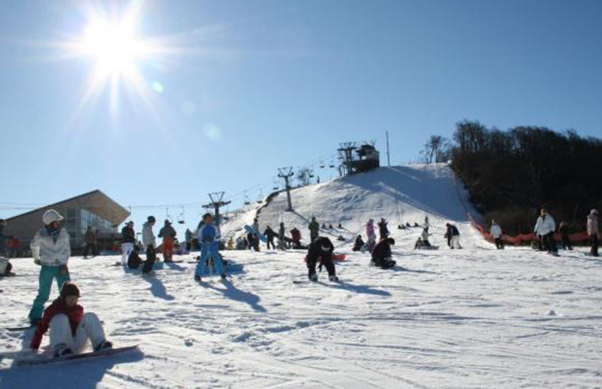 Una pista de esquí nevada con gente esquiando y haciendo snowboard.