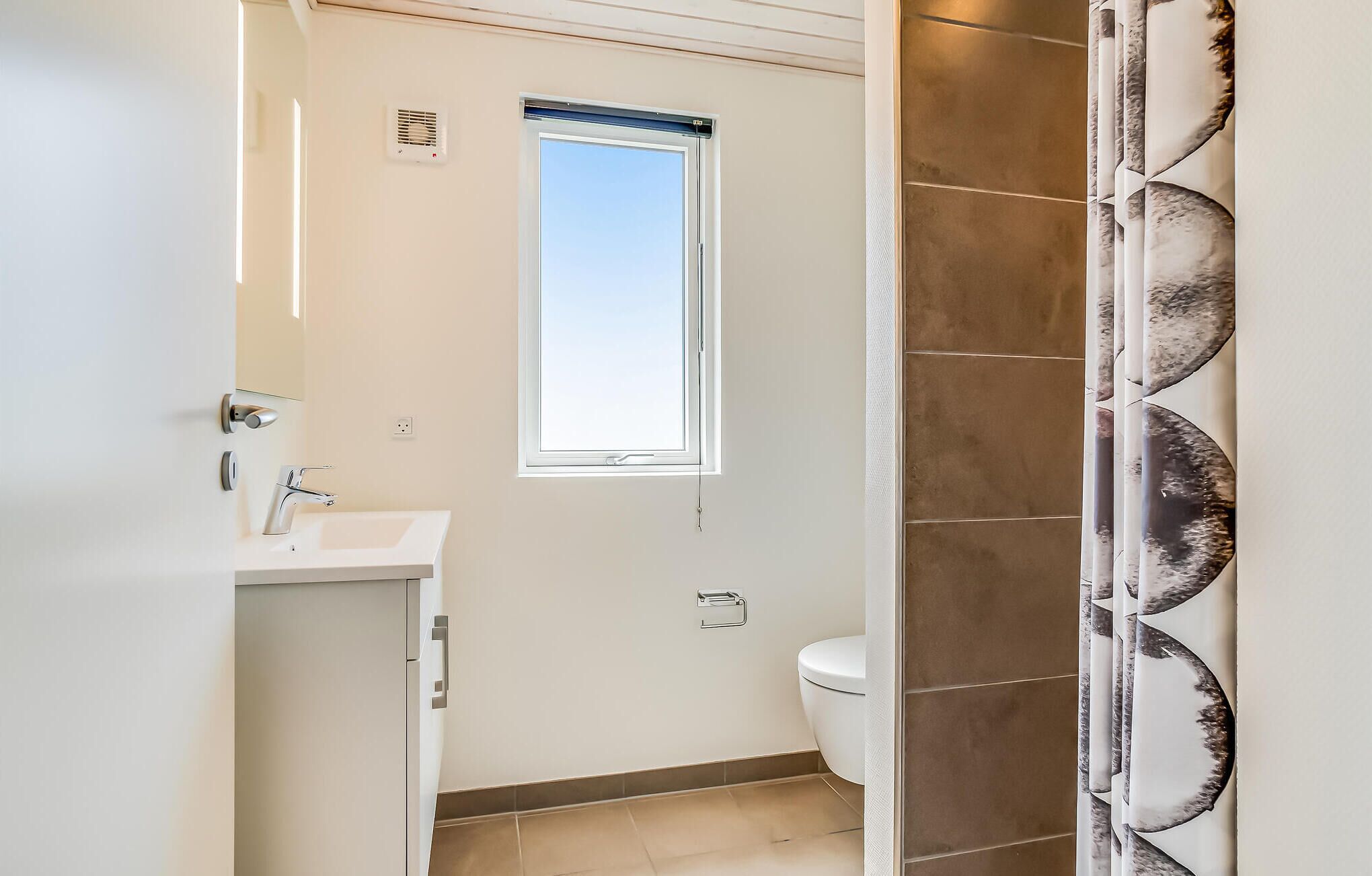 Een badkamer met een raam, toilet en wastafel.