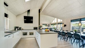 A modern kitchen with a central island, built-in ovens, and a dining area with chairs and tables. - Lovely home in Nørre Nebel with sauna (Nørre Nebel)