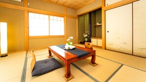 Ein traditioneller japanischer Raum mit Tatami-Bodenbelag, einem niedrigen Holztisch, einer gepolsterten Sitzbank und einer Schiebetür.