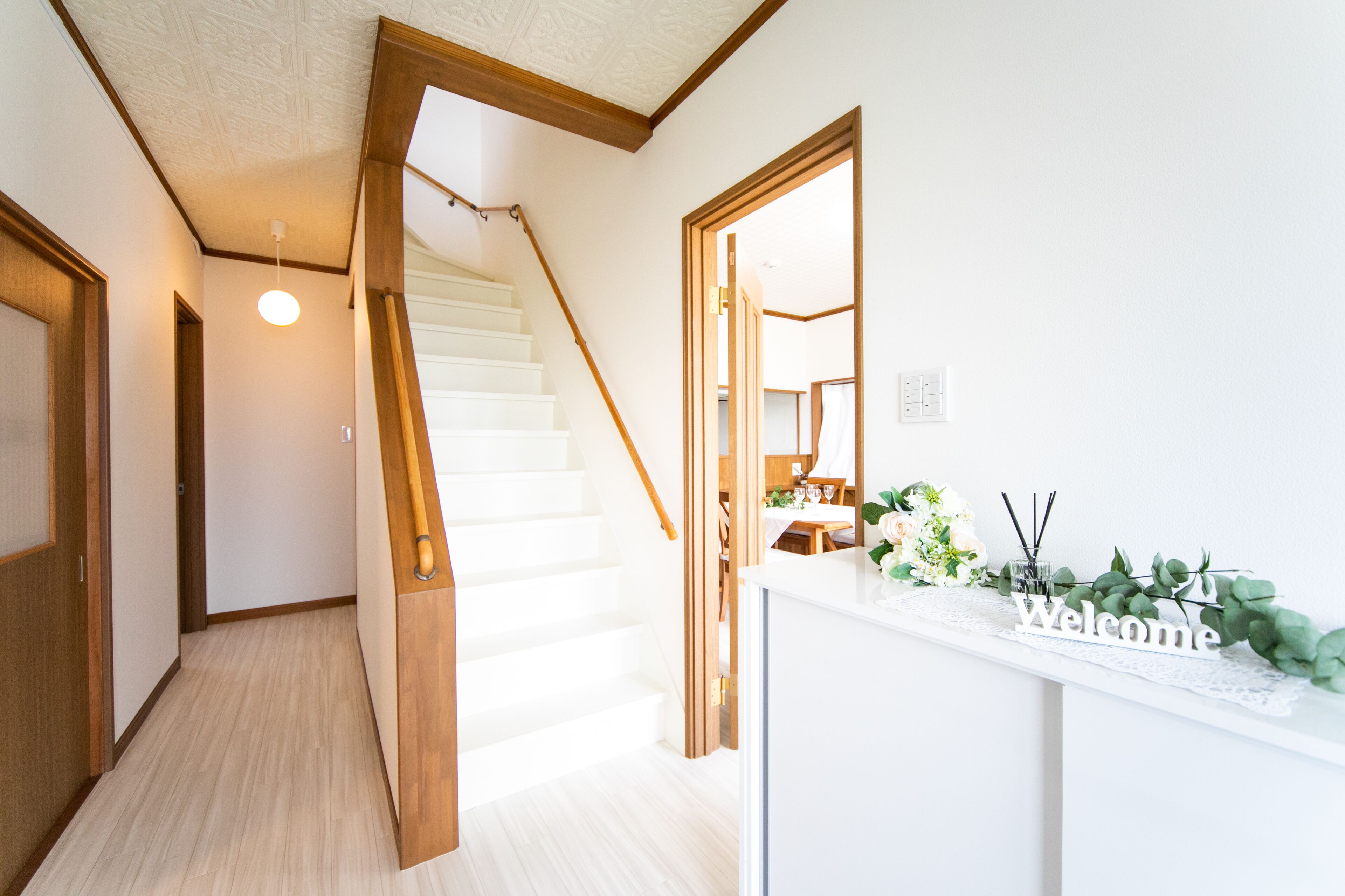 Un interior moderno con una escalera, un mostrador de recepción con un letrero que dice 'Welcome' y vistas a un comedor.