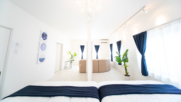 Ein modernes Hotelzimmer mit einem großen Bett, einer Chandelüster, einer Sitzecke und einer Topfpflanze.