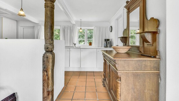 Eine Küche mit weißen Schränken, einer Holz Arbeitsplatte, einem großen Spiegel und einem Fenster mit Vorhängen.