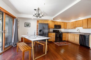 A kitchen with wooden cabinets, a stainless steel refrigerator, a microwave, and a dishwasher. - Charming Lower Unit Condo: Stays Cool in Summer! (Steamboat Springs)