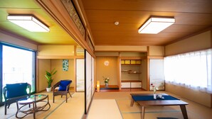 A traditional Japanese room with tatami flooring, a low table, a sofa, and a chair. - Awaji Seaside Resort in Shiduki (Awaji)