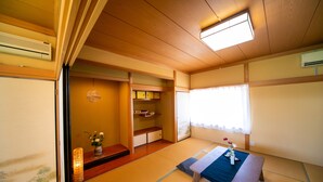 A traditional Japanese room with tatami flooring, a low wooden table, a bench, and a sliding door leading to a small storage area. - Awaji Seaside Resort in Shiduki (Awaji)