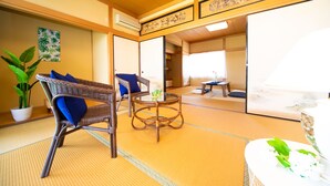 A traditional Japanese room with tatami flooring, a low table, and a wicker chair. - Awaji Seaside Resort in Shiduki (Awaji)